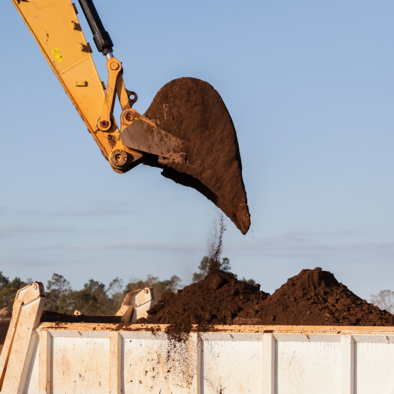 Godet déversant de la terre sur un chantier